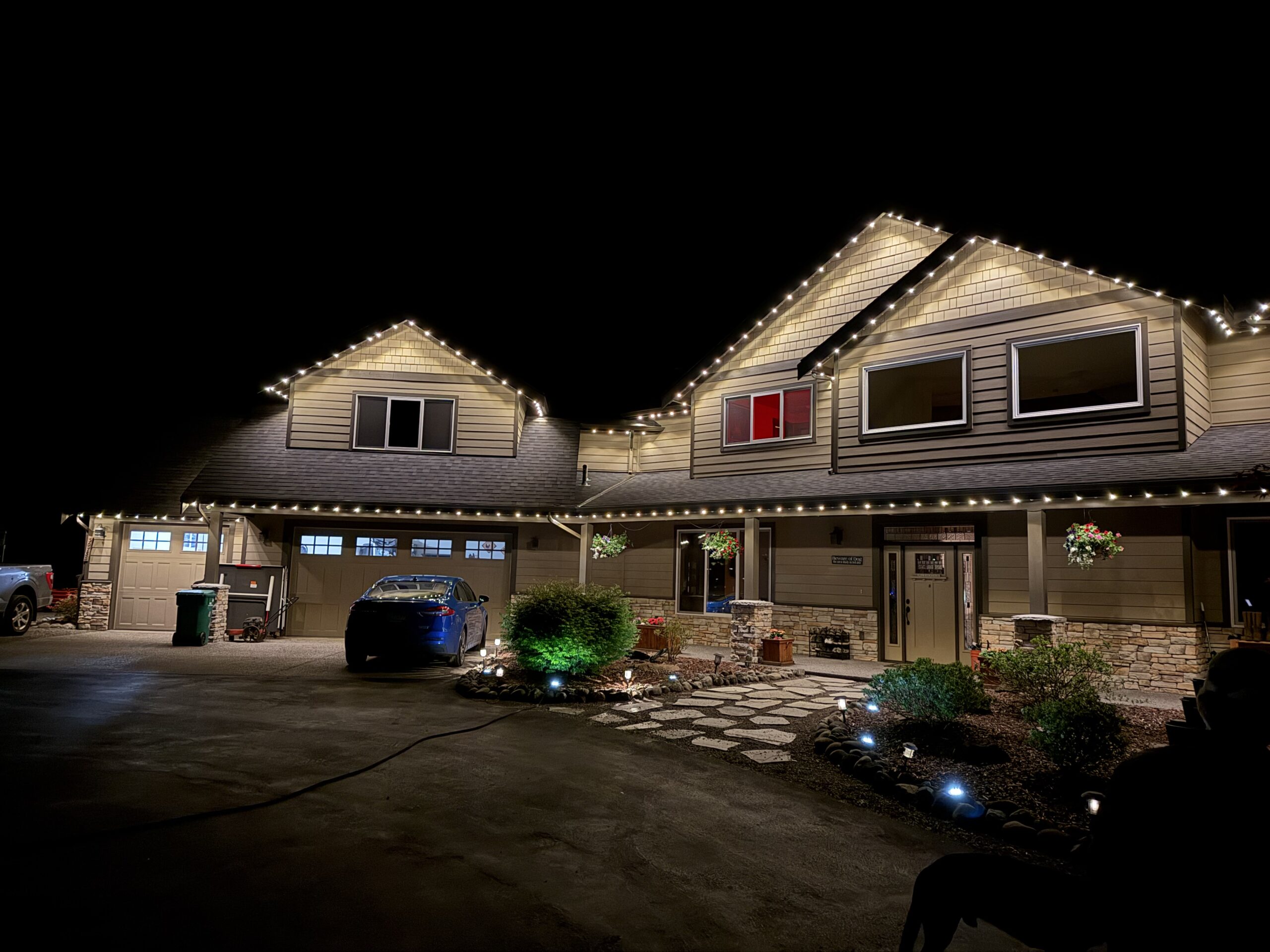 Single-family home with professionally installed permanent LED outdoor lighting illuminating the roofline and architectural features at night